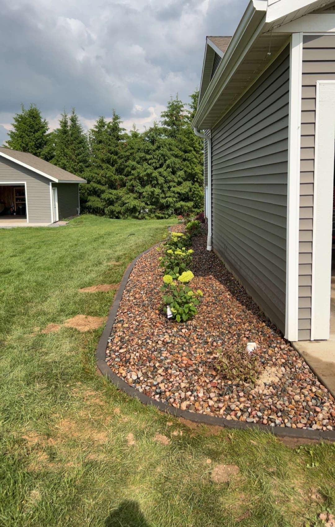 Landscaped garden border with decorative rocks and flowering plants beside house exterior.
