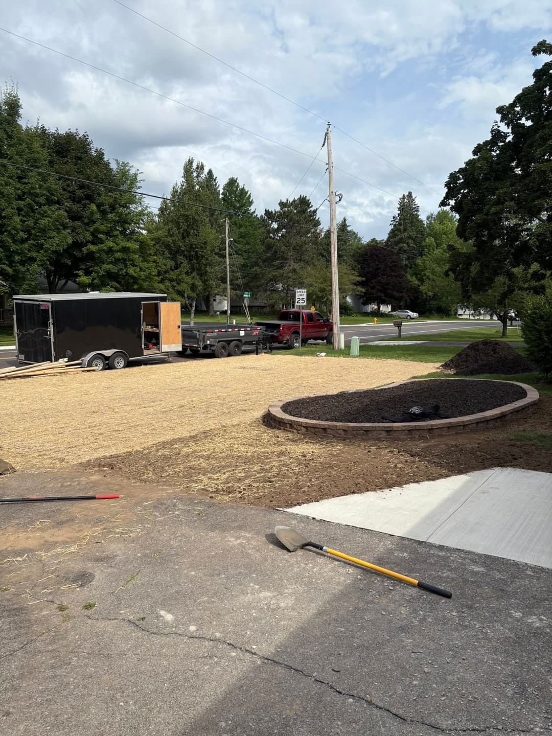 Landscape preparation with a trailer, gravel, and edging on a residential property.