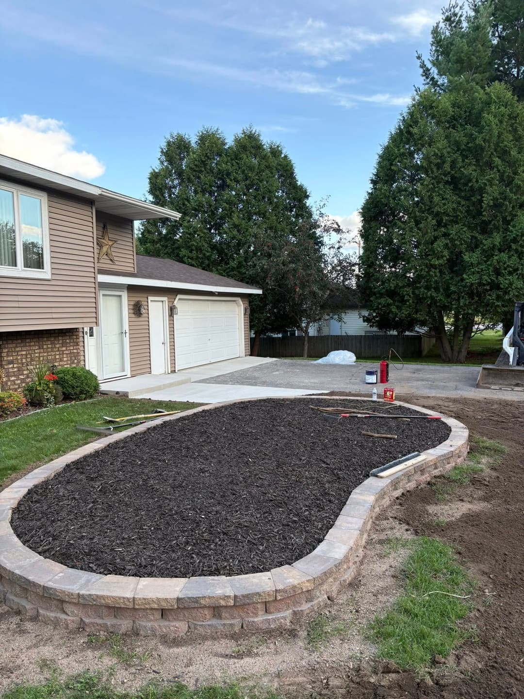 Landscaped garden bed with mulch and stone edging outside a residential home.