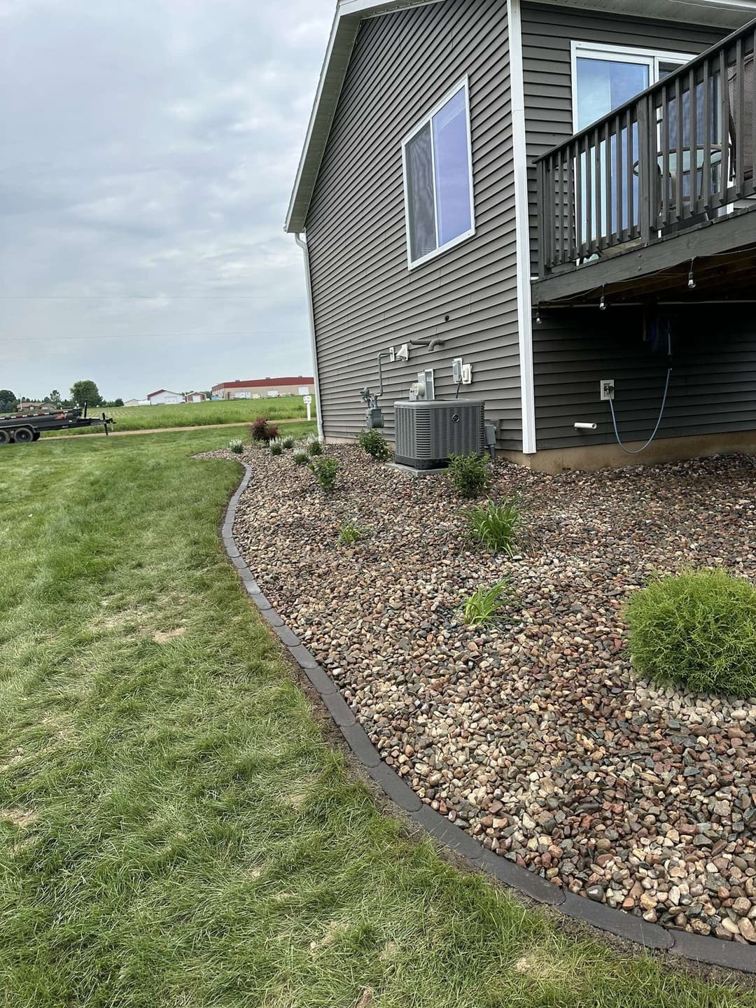 Landscape featuring gravel beds, plants, and a home exterior with air conditioning unit.