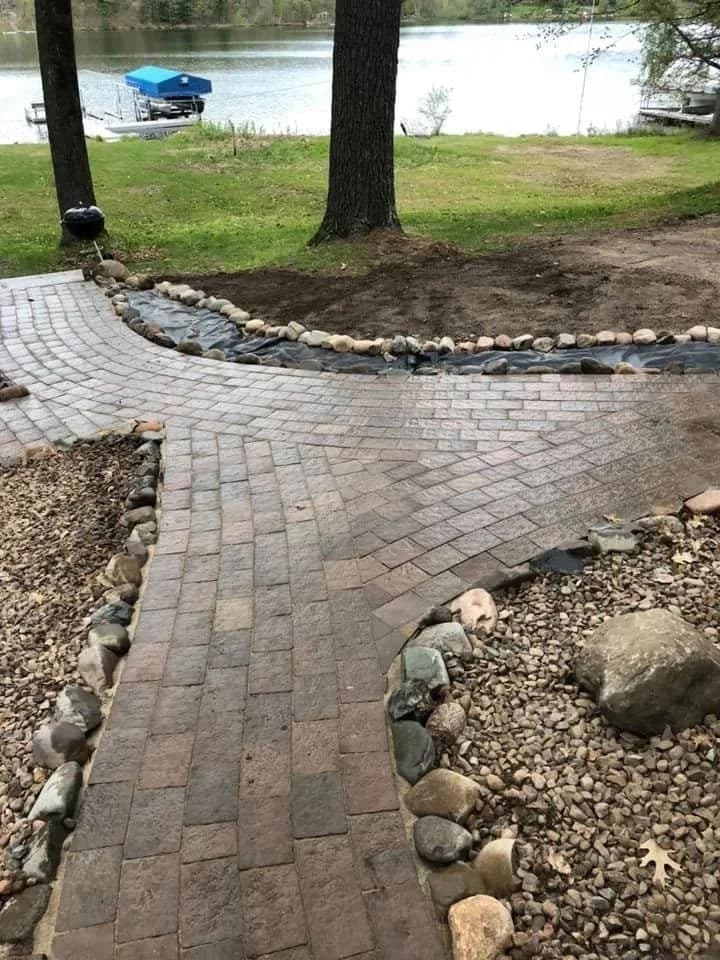 Paved path with stone borders leading to a serene lakeside view.