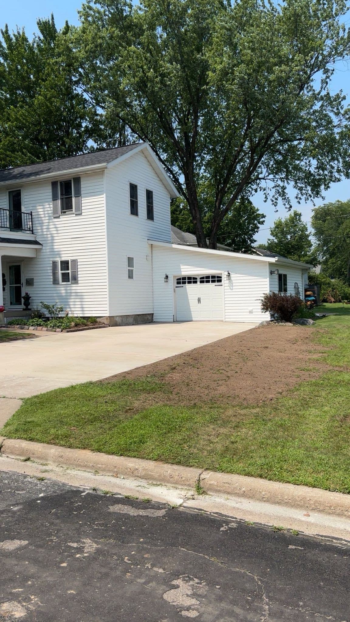 Two-story white house with garage and freshly landscaped yard on a sunny day.